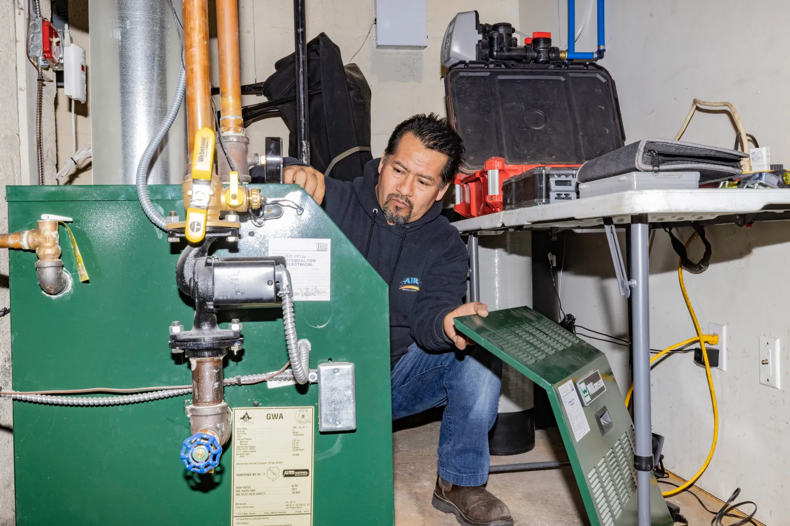 Licensed boiler service technician performing maintenance on residential hot water boiler in North Jersey